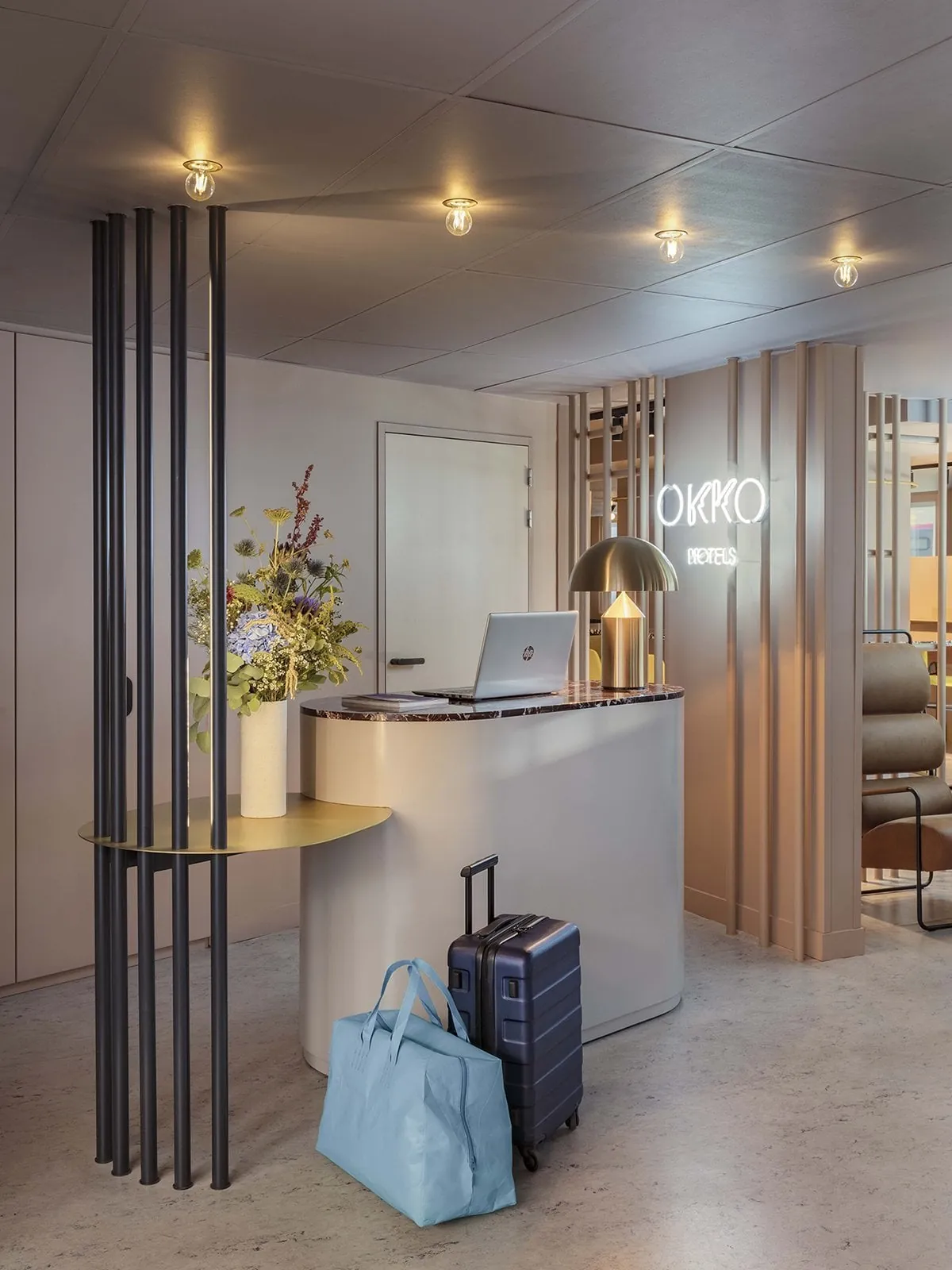 Reception area of the OKKO Hotels Paris Gare de l'Est with a counter, a neon OKKO sign and wooden slatted partitions