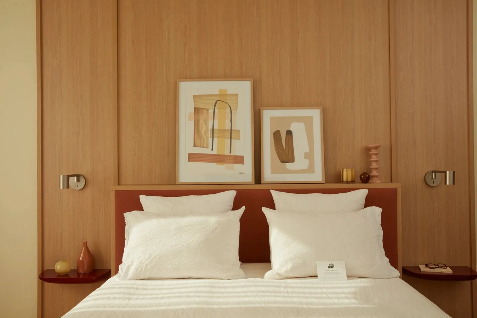 Guest room at the OKKO Hotels Paris Rosa Parks with a warm wooden wall, a terracotta headboard and framed abstract art