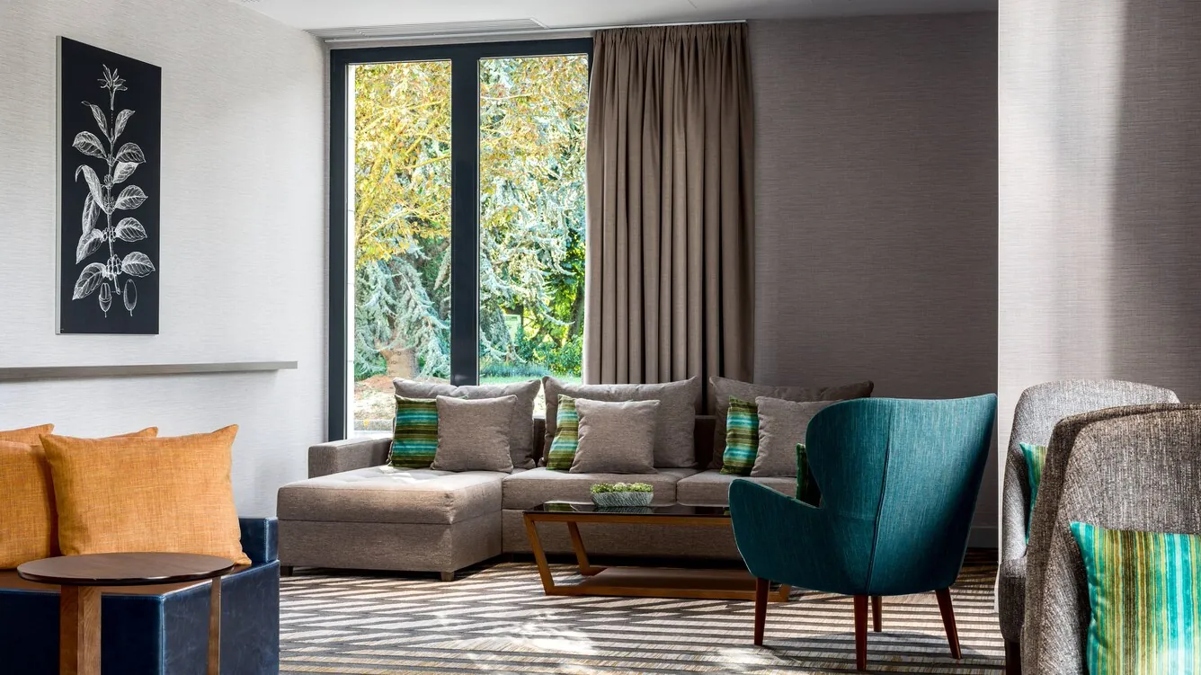 Breakout lounge at the Paris Marriott Charles de Gaulle Airport Hotel with green armchairs and a sofa