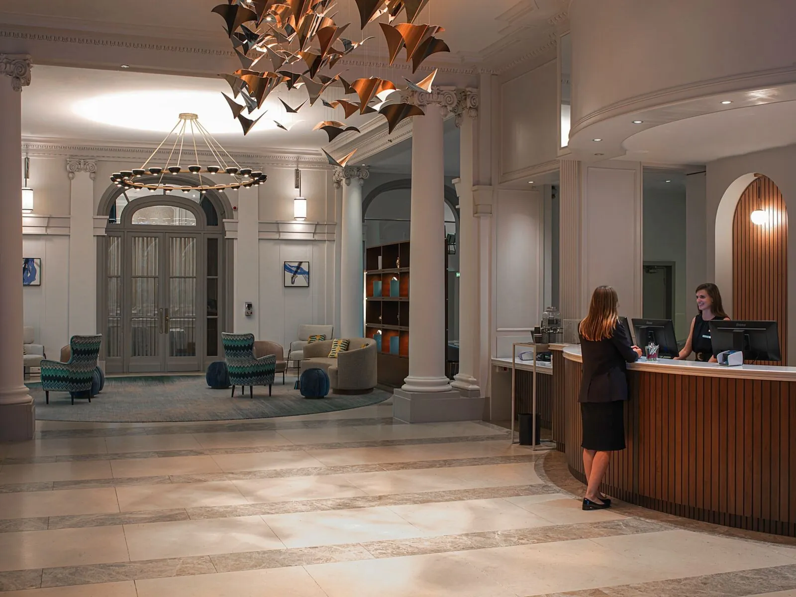 Reception desk and lobby of the Paris Marriott Opera Ambassador Hotel, with a sculpted chandelier and sofas