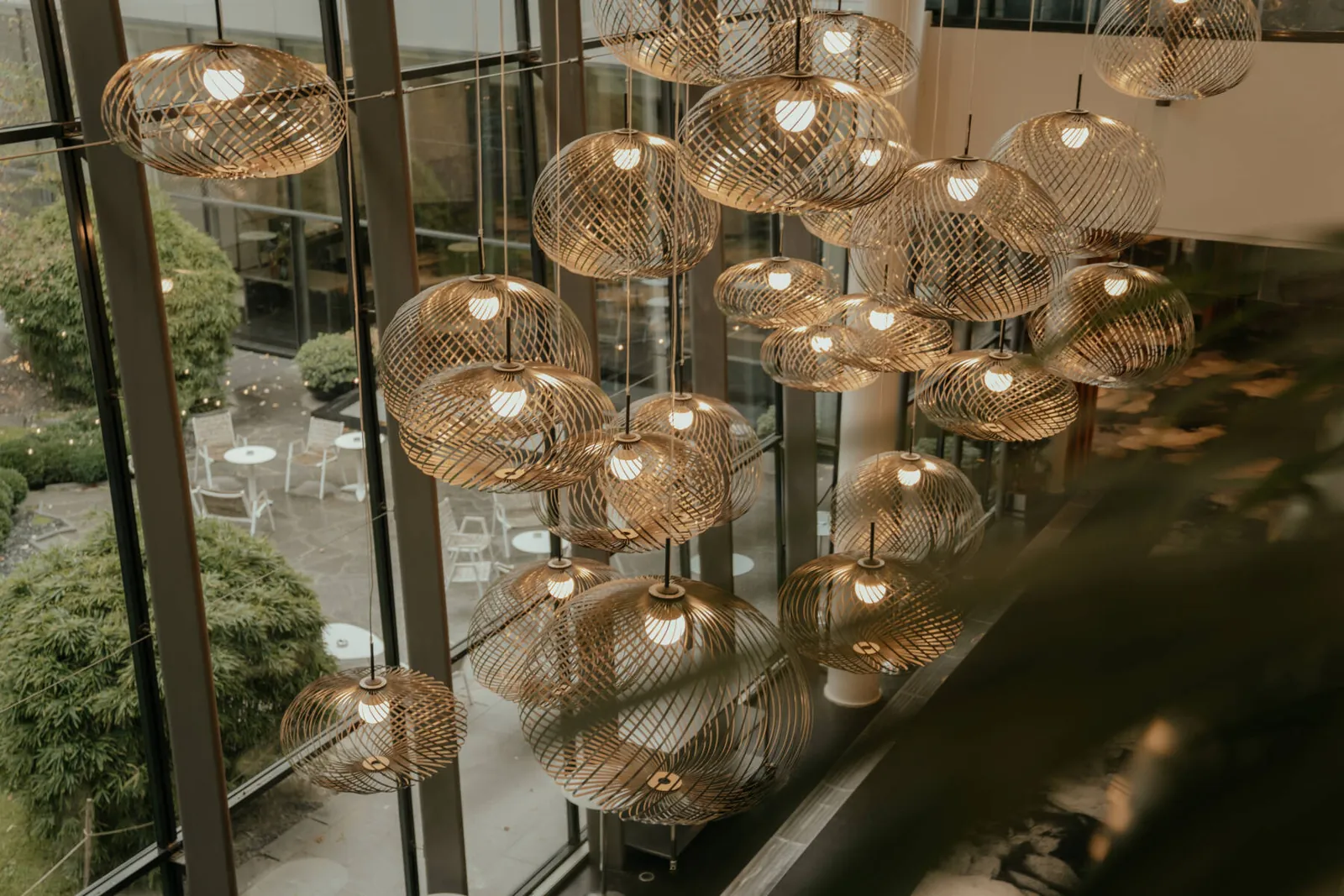 Brass pendant lanterns in the atrium of Pullman Paris Centre-Bercy, with a view onto the garden