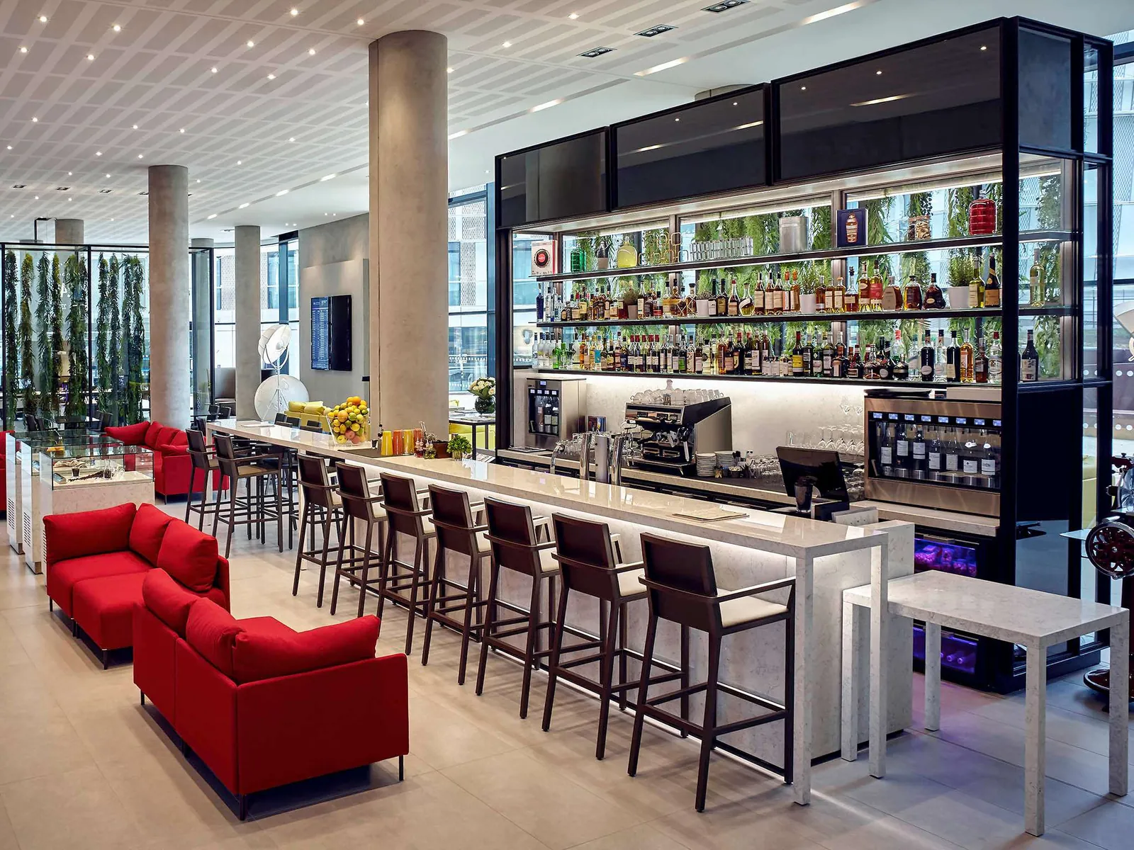 Bar and lounge at Pullman Paris Roissy CDG Airport with red sofas, bar stools and backlit bottles