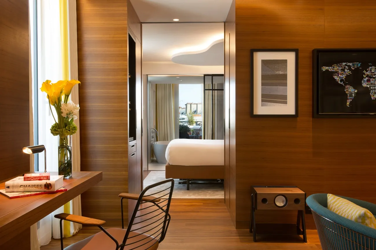 Room with wood-panelled wall, work desk and view through to the bed at Renaissance Paris République Hotel