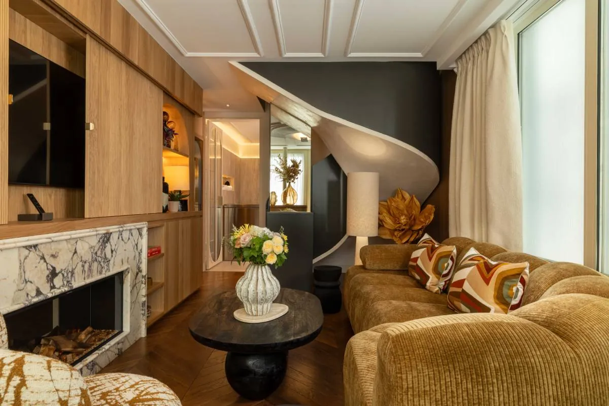 Living room of a suite at Hôtel & Spa Royal Madeleine in Paris, with a marble fireplace and staircase