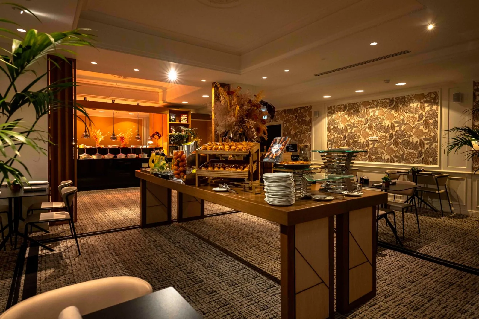 Breakfast buffet lounge with warm wood counters, dried flowers and stacked plates at Sofitel Le Scribe, Paris