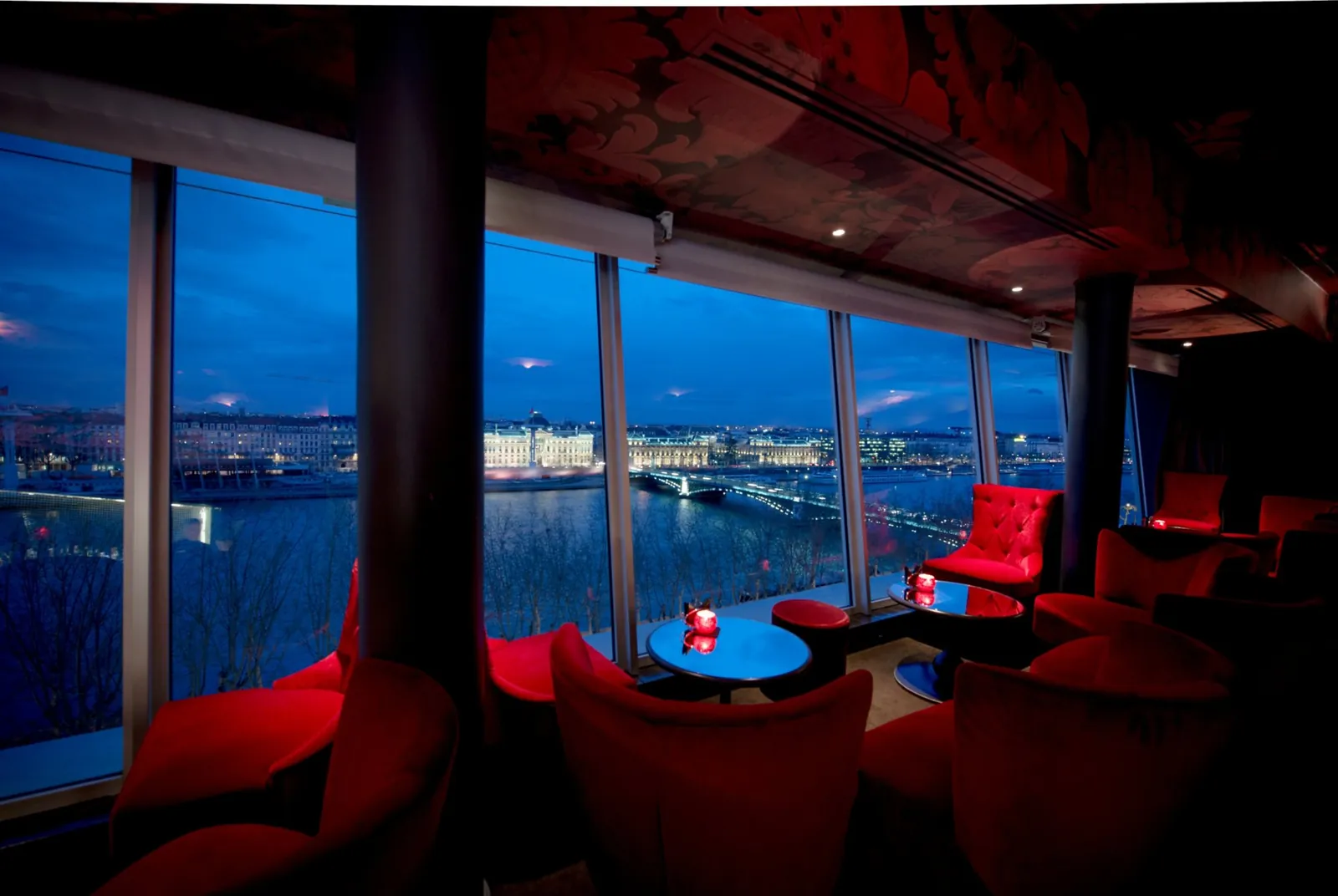 Lounge bar with red armchairs and night view over Lyon at Sofitel Lyon Bellecour