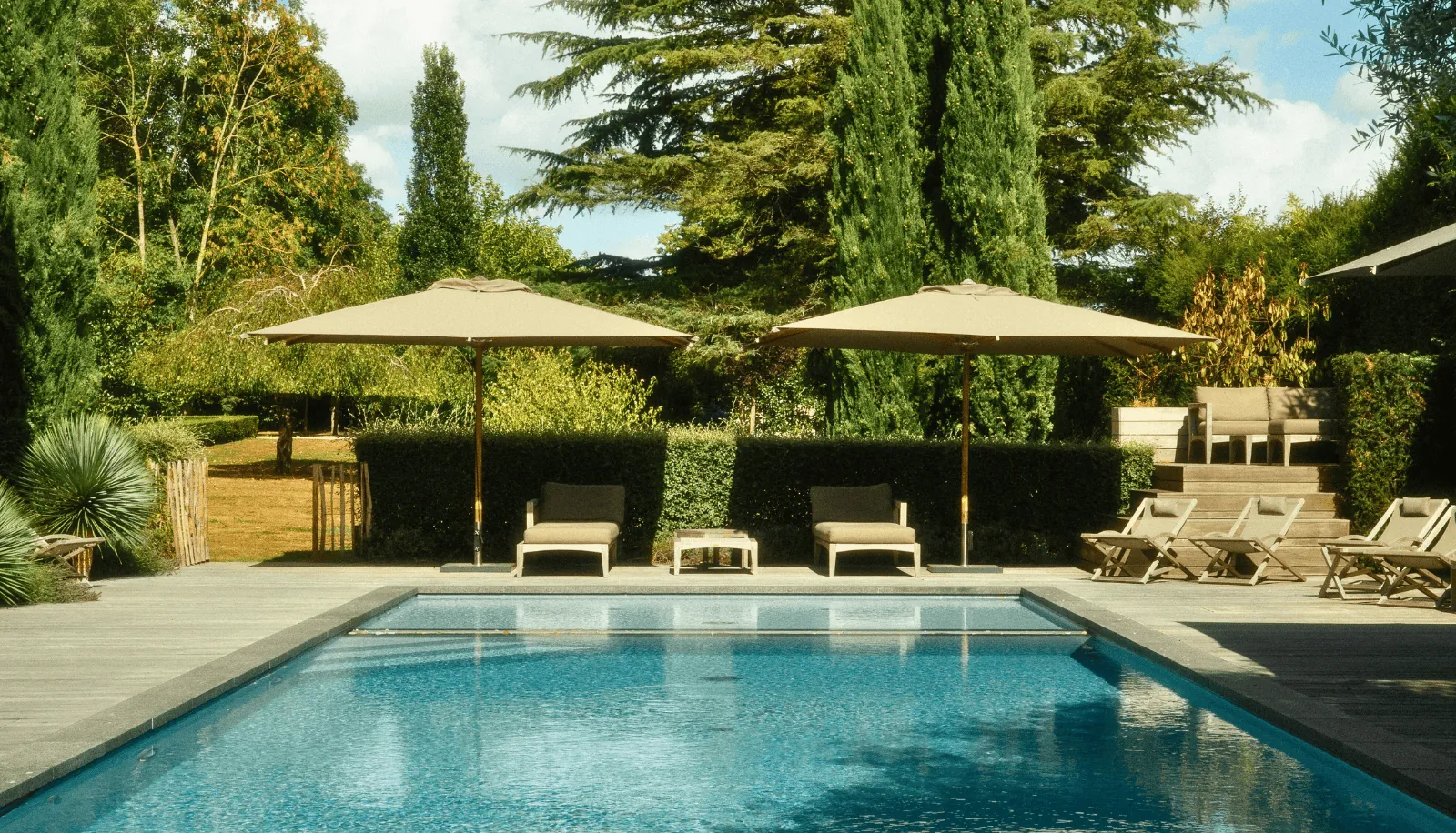 Swimming pool with parasols and sun loungers at Villa des Glycines, Île-de-France