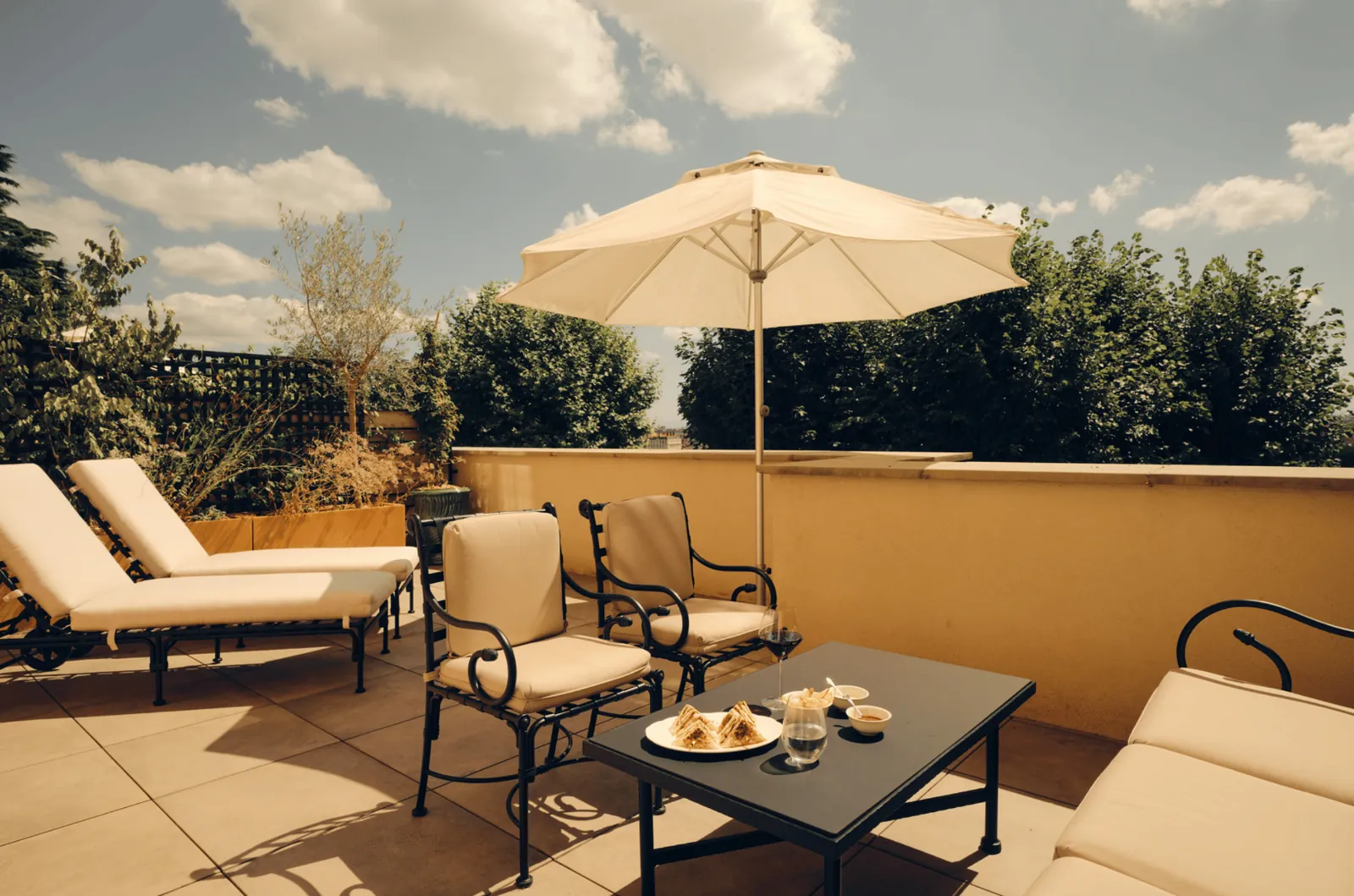 Private terrace with cream armchairs, a parasol and lounge chairs at Villa Florentine, Lyon