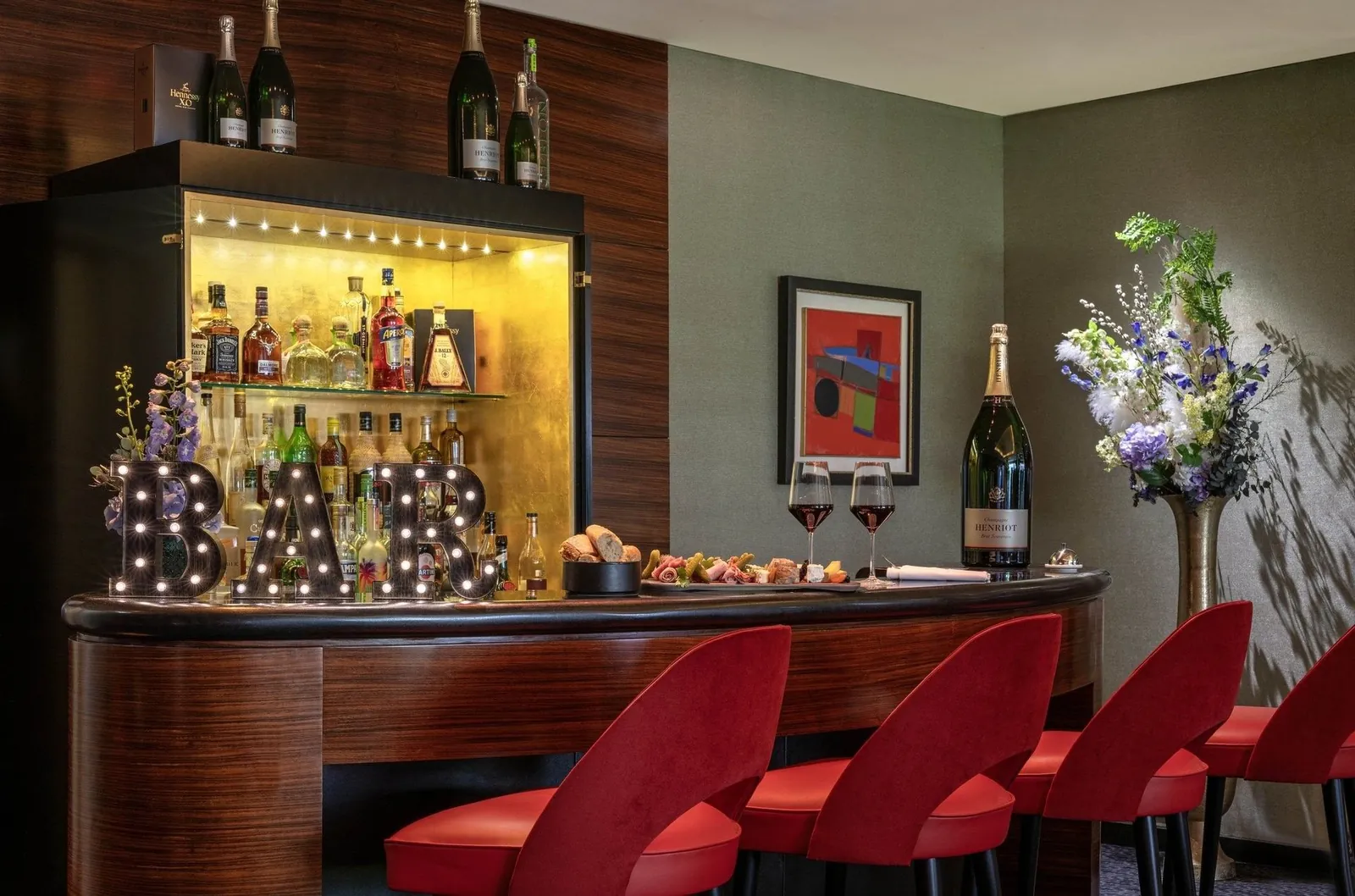 Bar of Warwick Paris Champs-Élysées with backlit bottle shelves and red leather bar stools