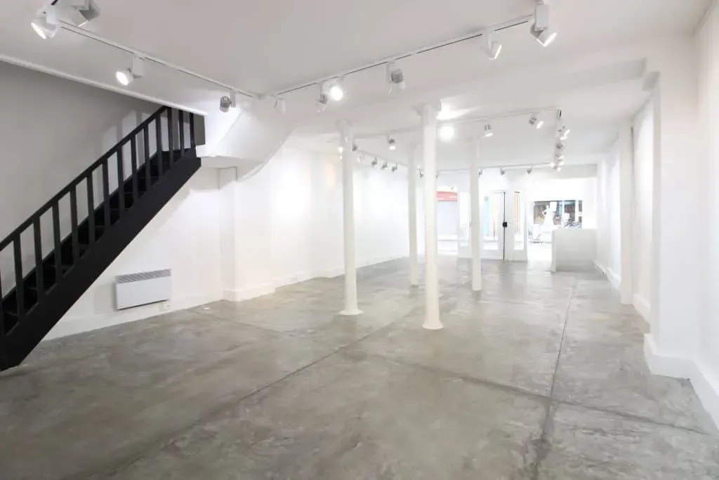 White room with a black staircase and a concrete floor