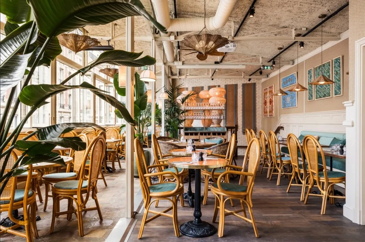 Bright brasserie room with plants and rattan chairs