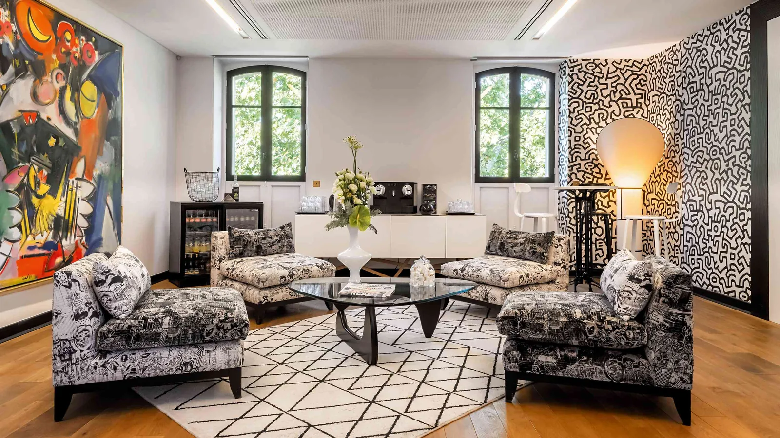Light Atelier lounge with patterned armchairs, a glass coffee table and abstract art
