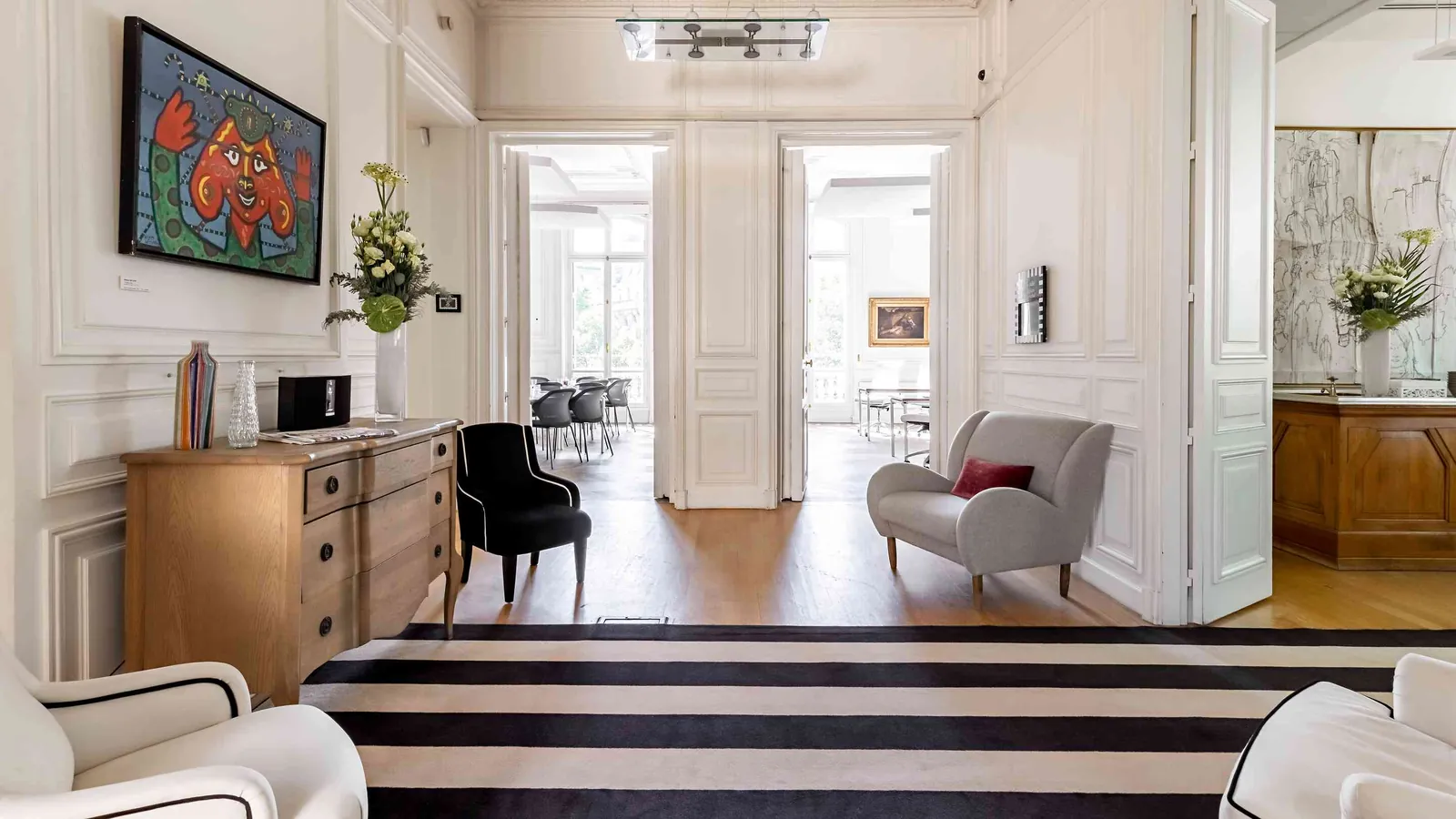 Light Atelier hallway with a striped rug, paintings and a light-filled reception room