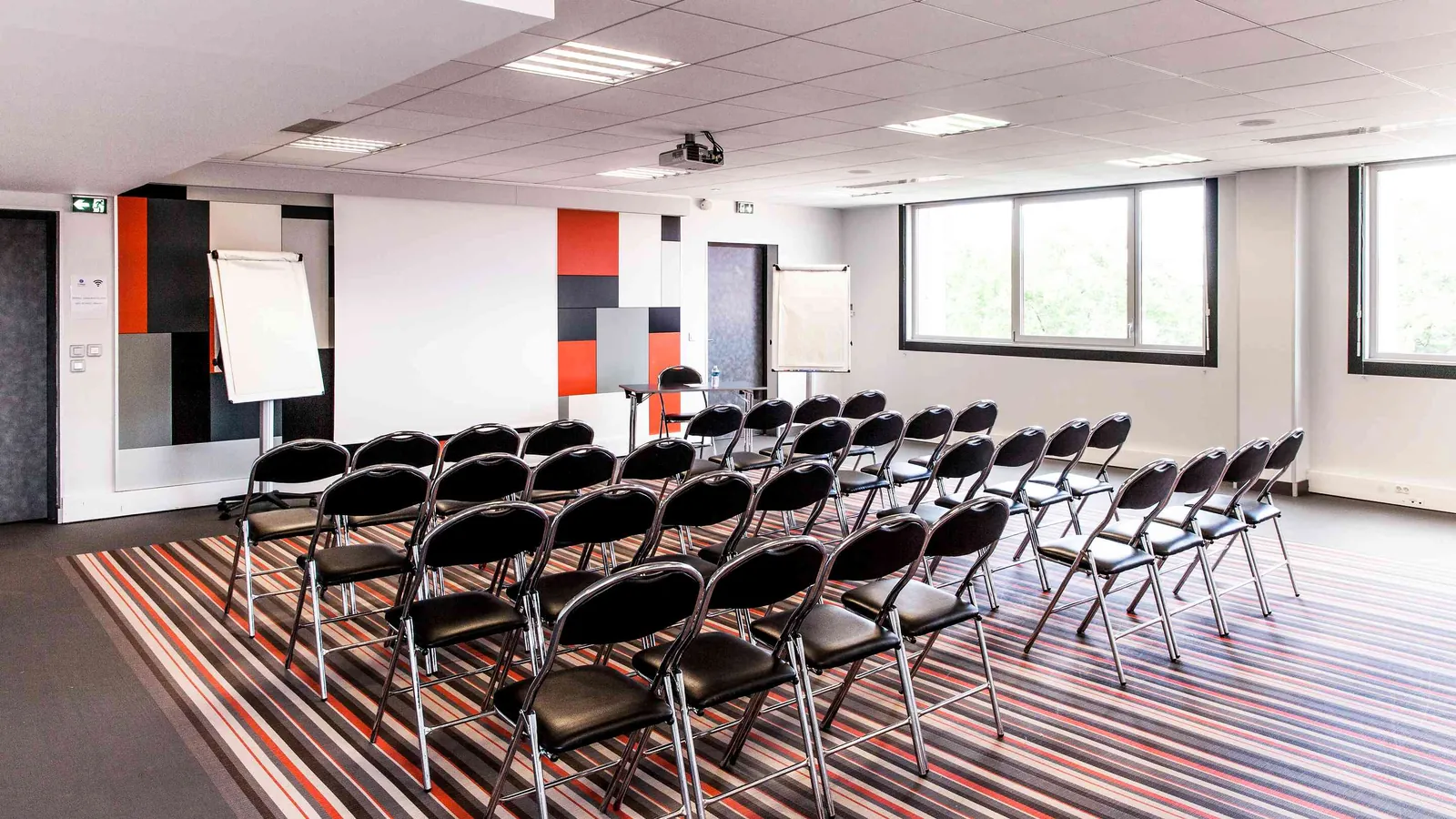 Northern Workshops meeting room with a projection screen, folding chairs and a striped carpet