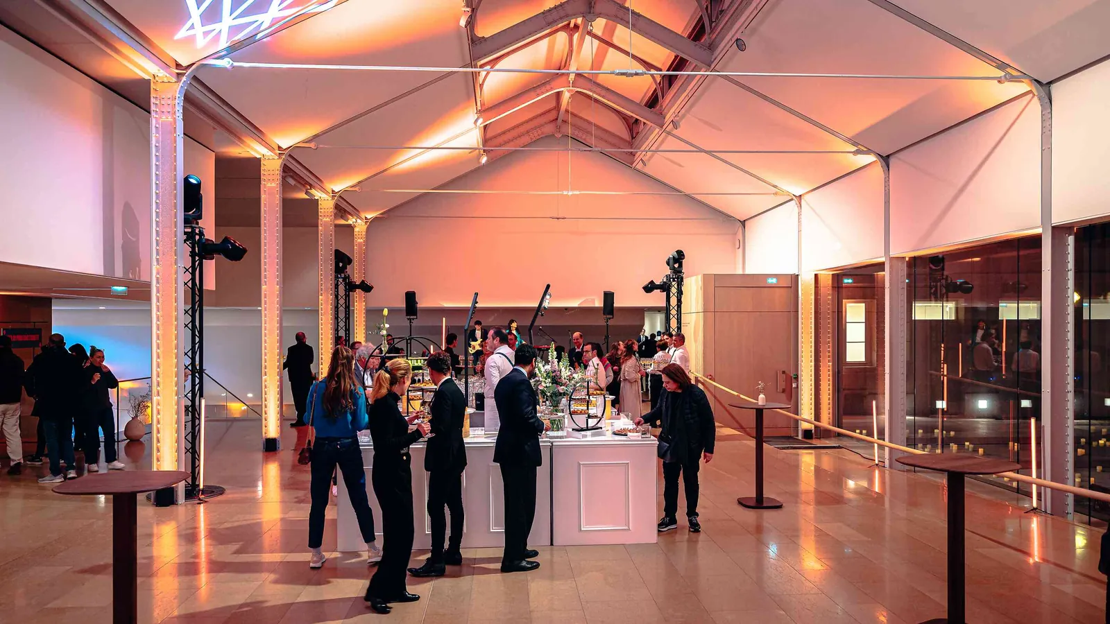 Left Bank Atrium reception area with warm uplighting, a drinks counter and standing guests