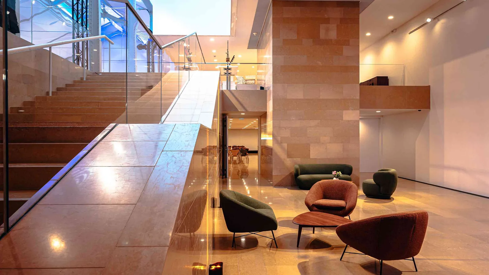Left Bank Atrium entrance hall with a glass-railed staircase and lounge armchairs