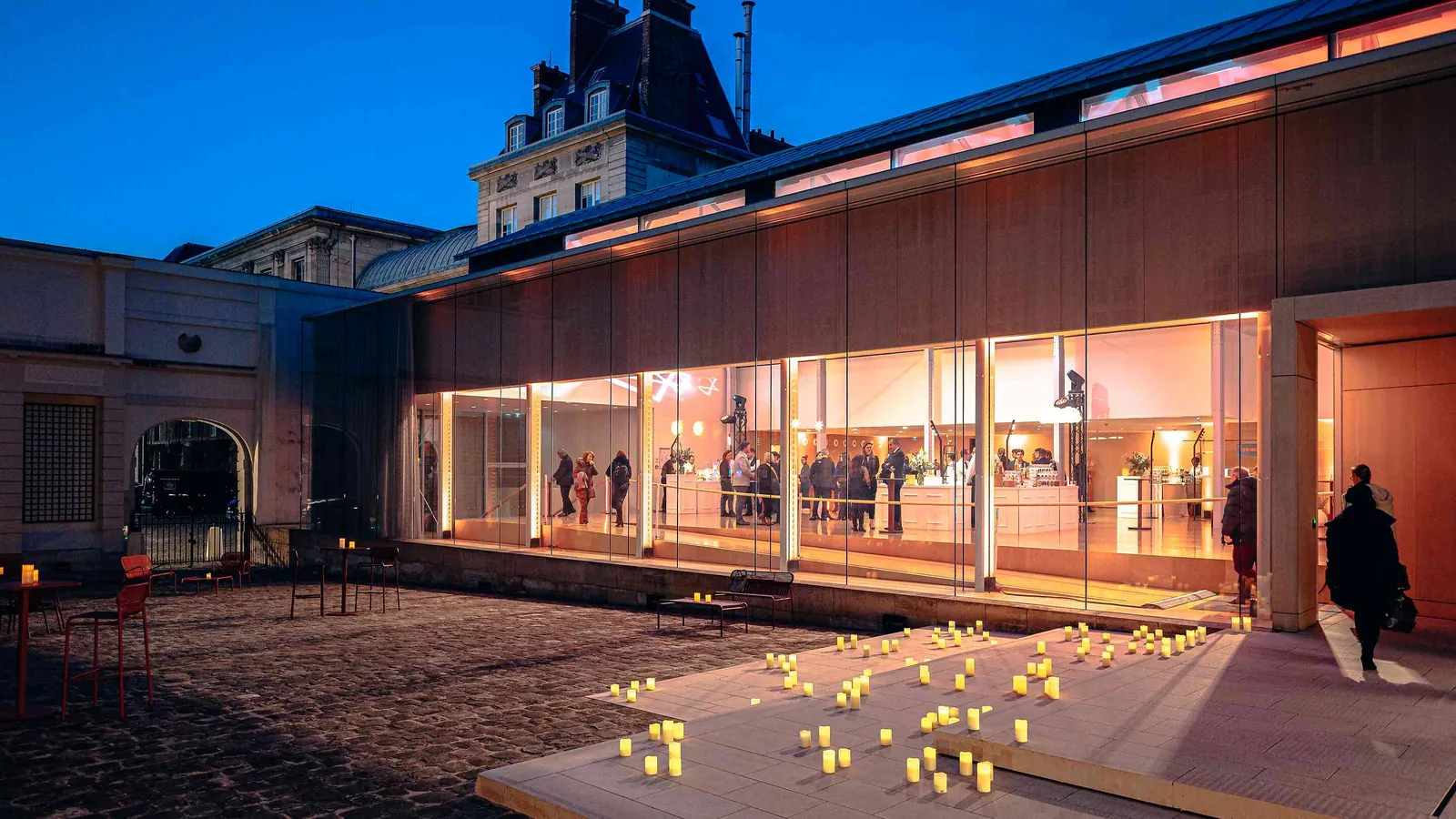 Left Bank Atrium exterior glowing at dusk, with its glazed pavilion lit from within