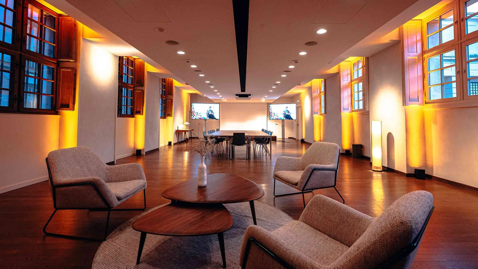 Left Bank Atrium lounge with armchairs, a round low table and warm wall lighting