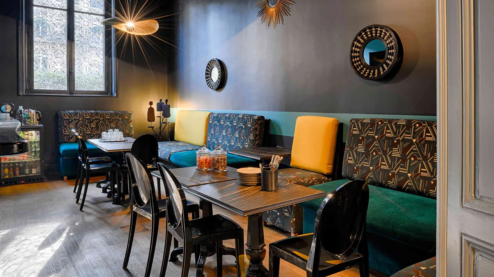 Discreet Circle dining room with a dark wooden table, teal banquette and round mirrors
