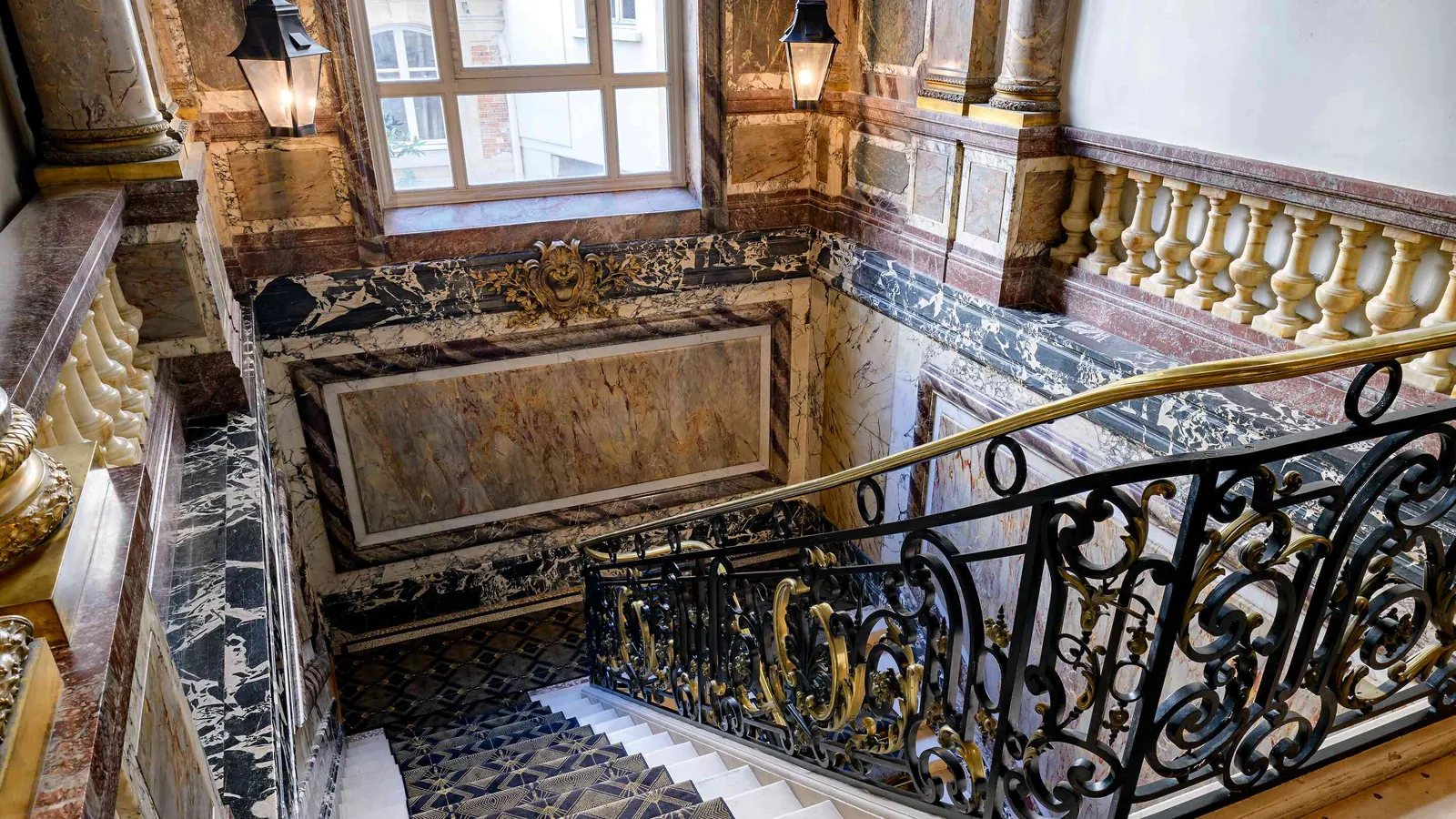 Discreet Circle marble staircase with a gilded balustrade and wrought-iron railing