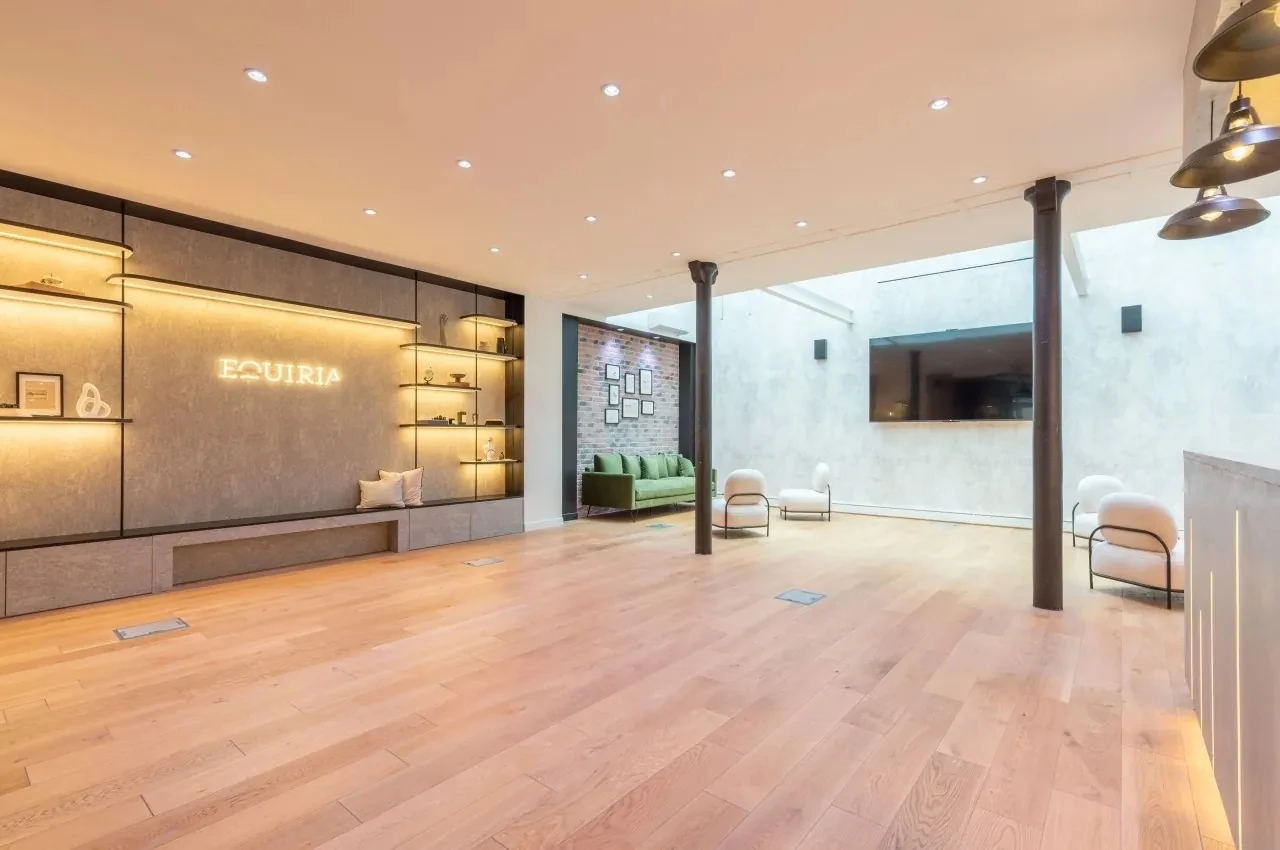 Main room with wood flooring, columns and a feature wall