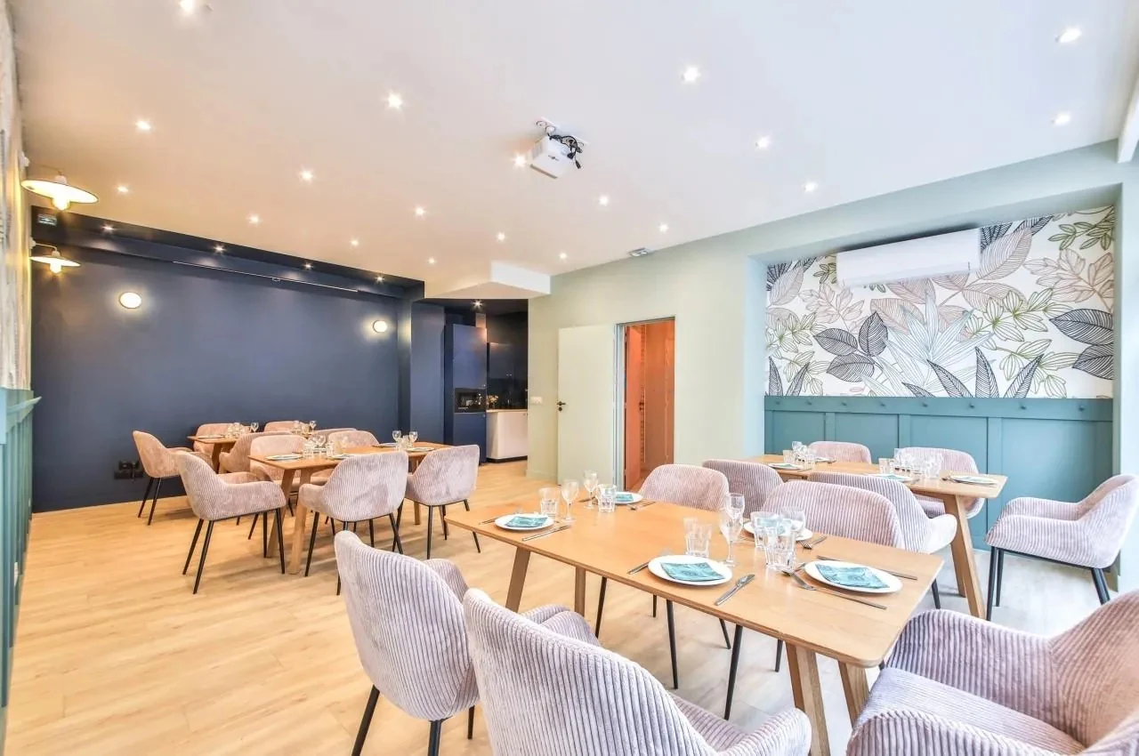 Room with dining tables, pink chairs and light wood flooring