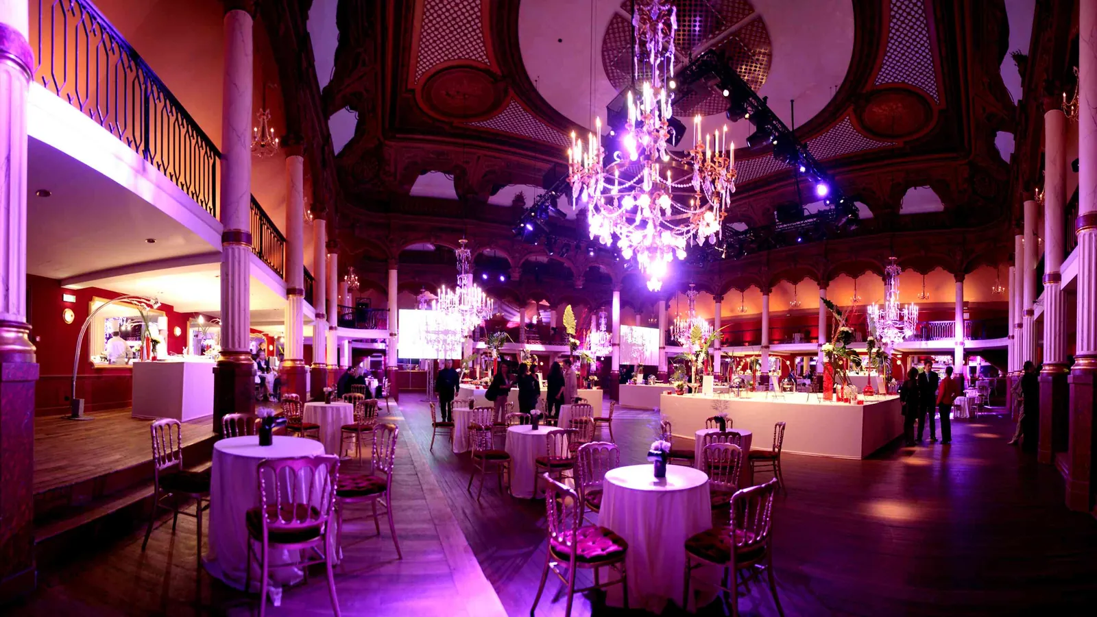 Étoile Grand Hall reception with violet lighting, chandeliers and round cocktail tables