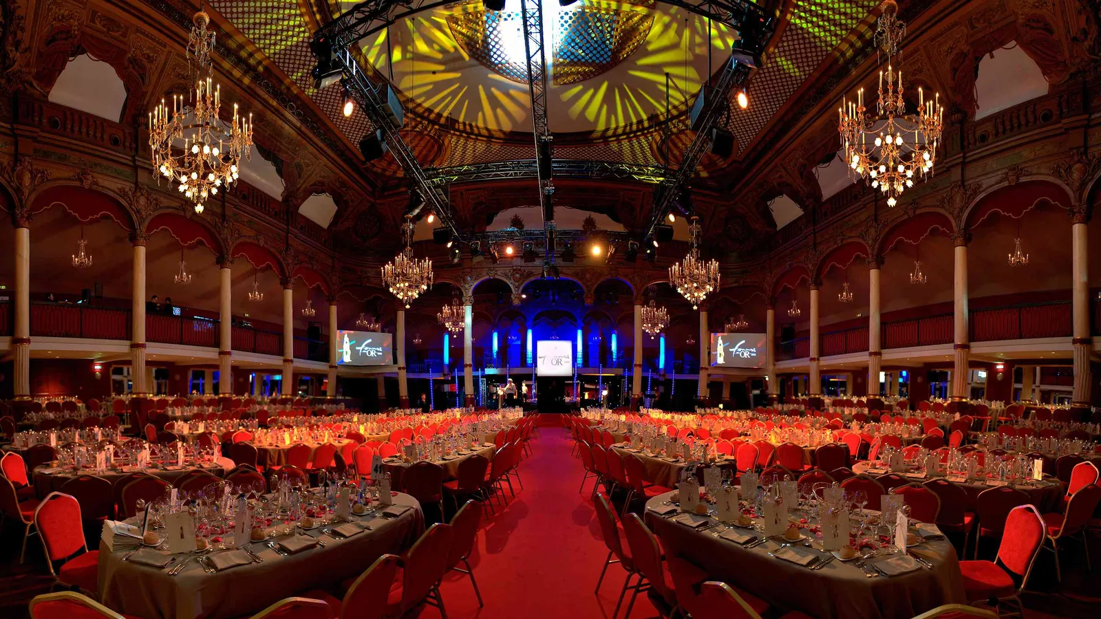 Étoile Grand Hall gala dinner under chandeliers, with long banquet tables and red chairs
