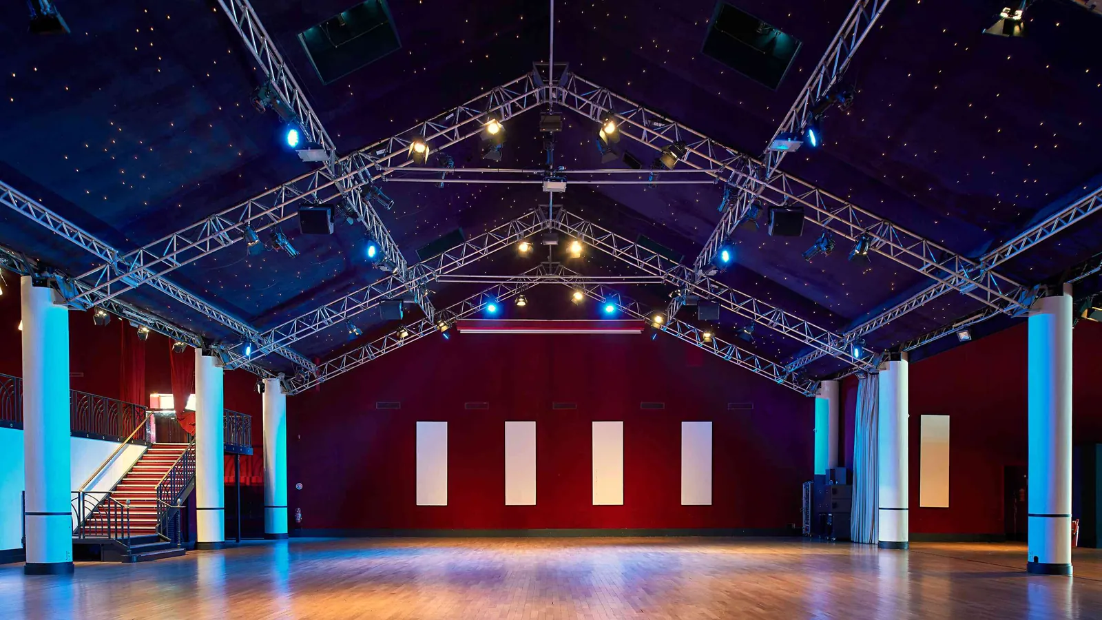 Seine Grand Halls empty hall with exposed trusses, a deep red back wall and steel columns