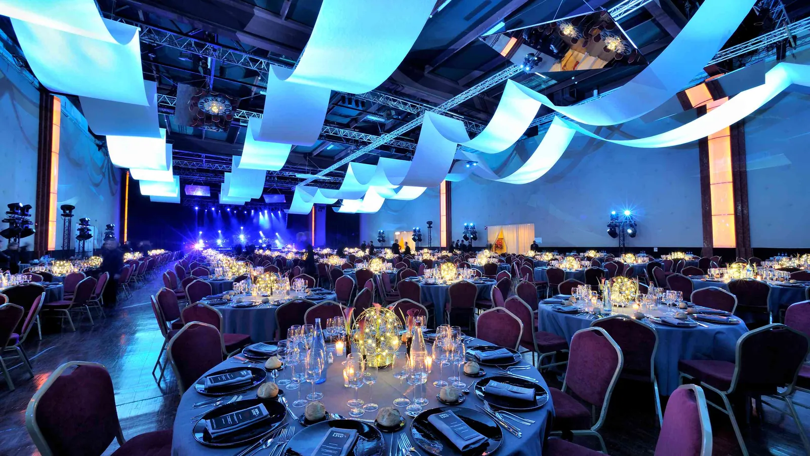 Seine Grand Halls banquet room with round tables, chairs and suspended light ribbons