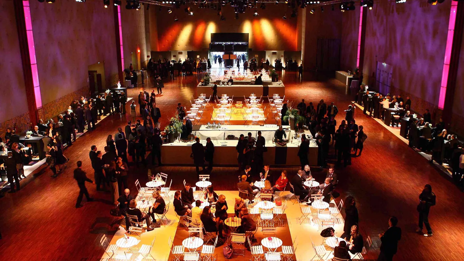 Seine Grand Halls gala set-up with long tables, a central buffet and warm stage lights
