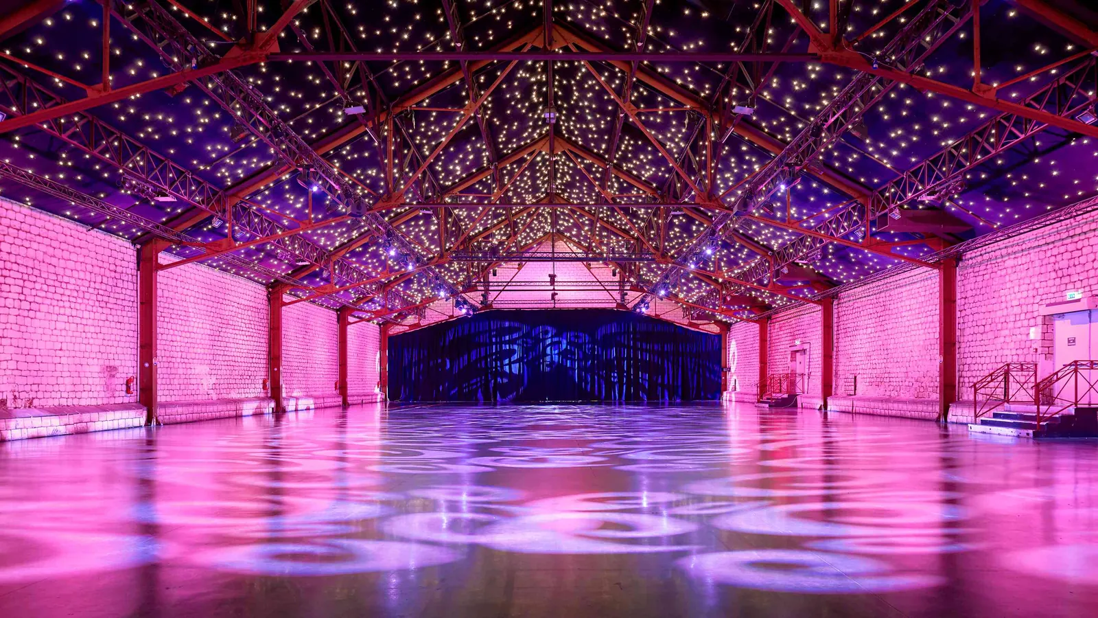 Seine Grand Halls main hall with a starry ceiling, exposed trusses and pink lighting