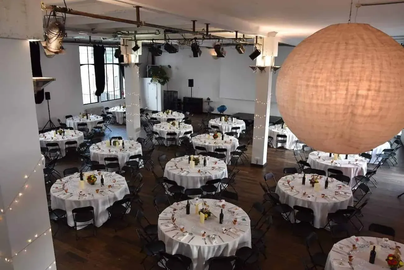 Banquet round tables set under exposed beams with string lights