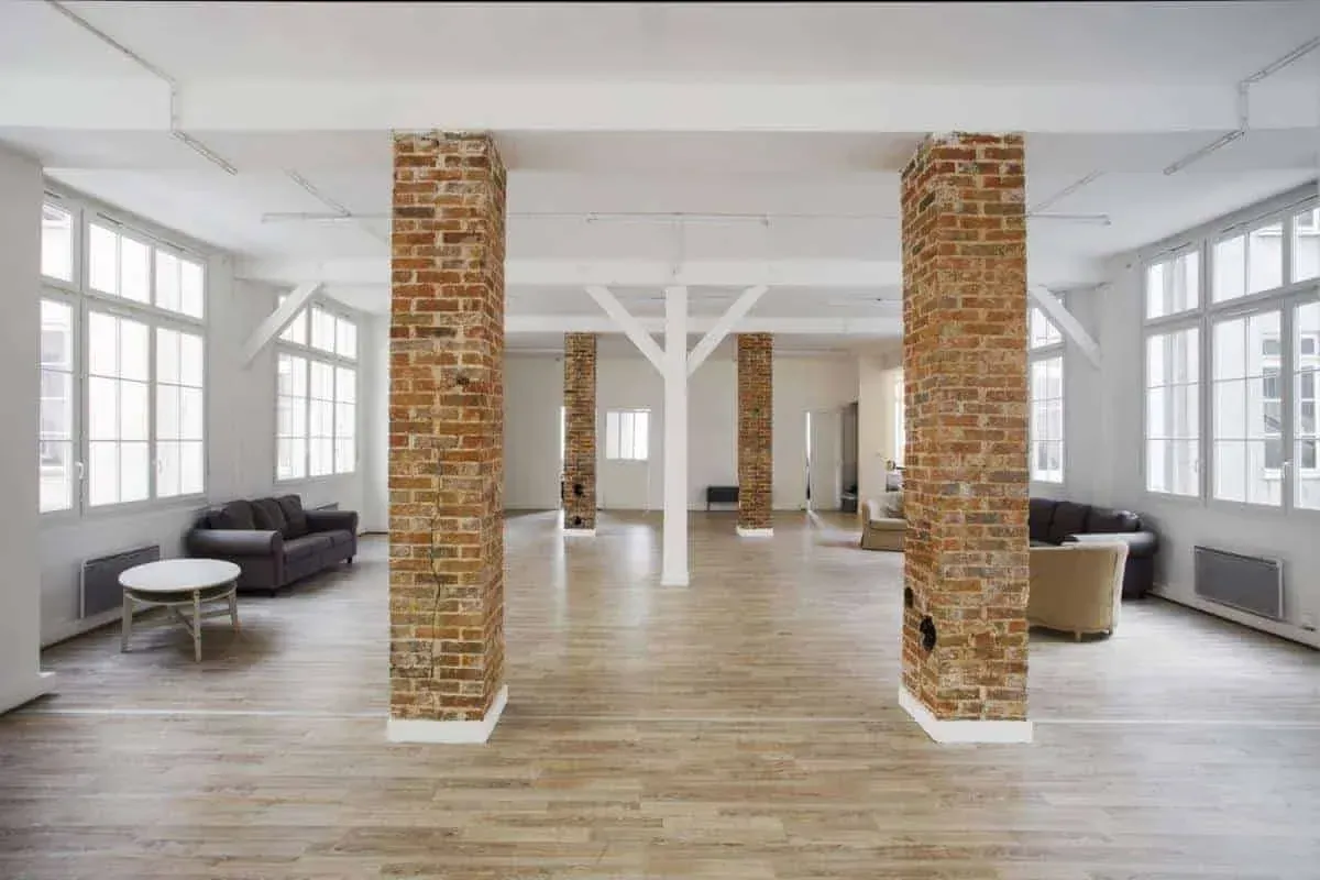 Loft with brick columns, sofas and a round coffee table by the windows