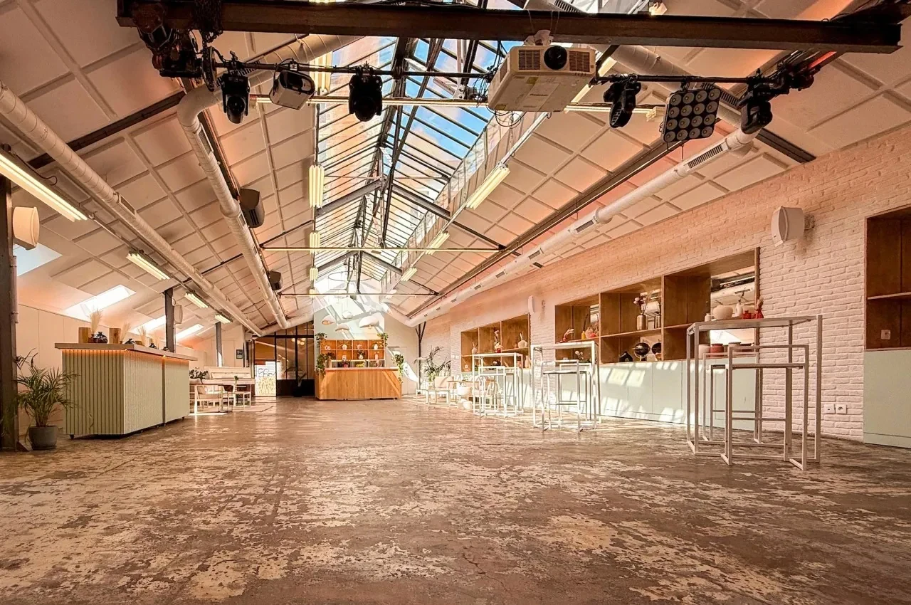 Long hall under a glass roof with stage rigging and daylight