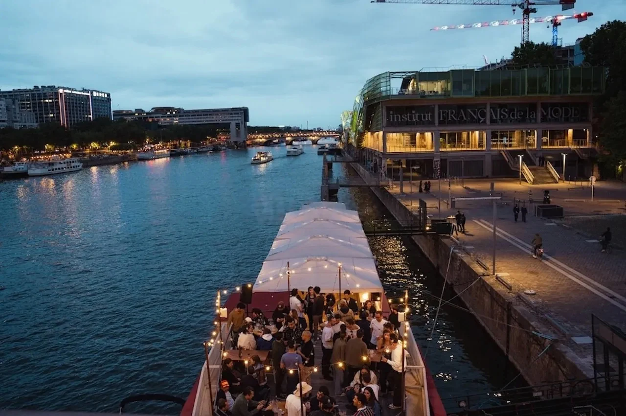 Riverside terrace at dusk with a boat and an illuminated facade