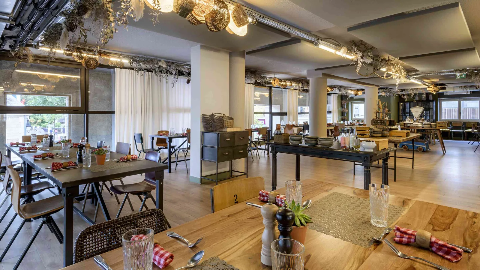 Workshop House dining room with a long timber table, mismatched chairs and fresh flowers