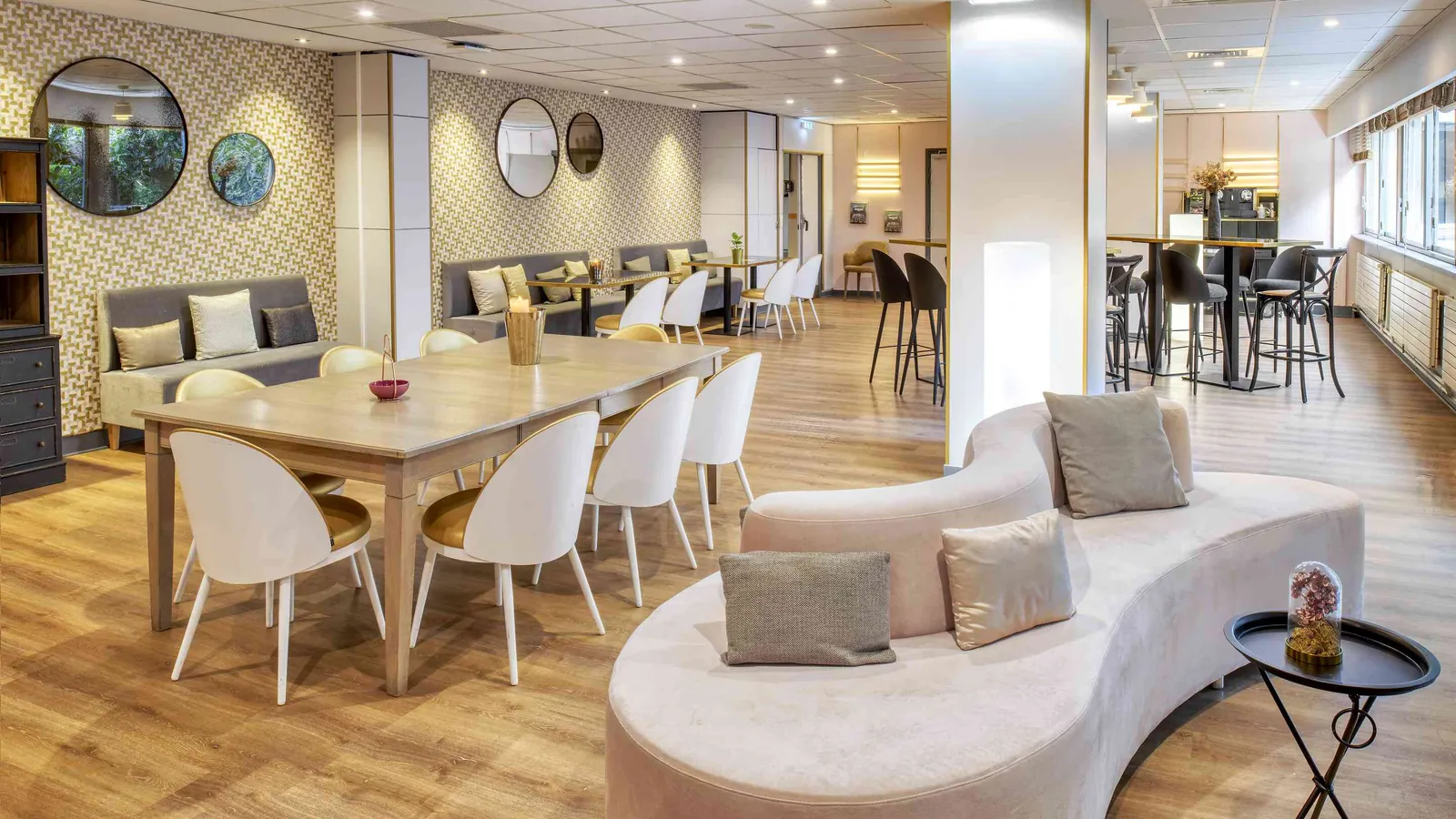 Golden House lounge with a curved cream sofa, a timber dining table and high stools nearby