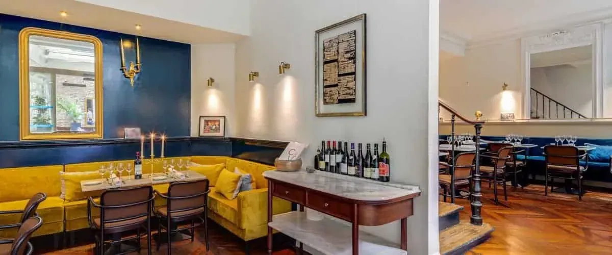 Lounge with blue walls, a yellow velvet sofa and a wine display