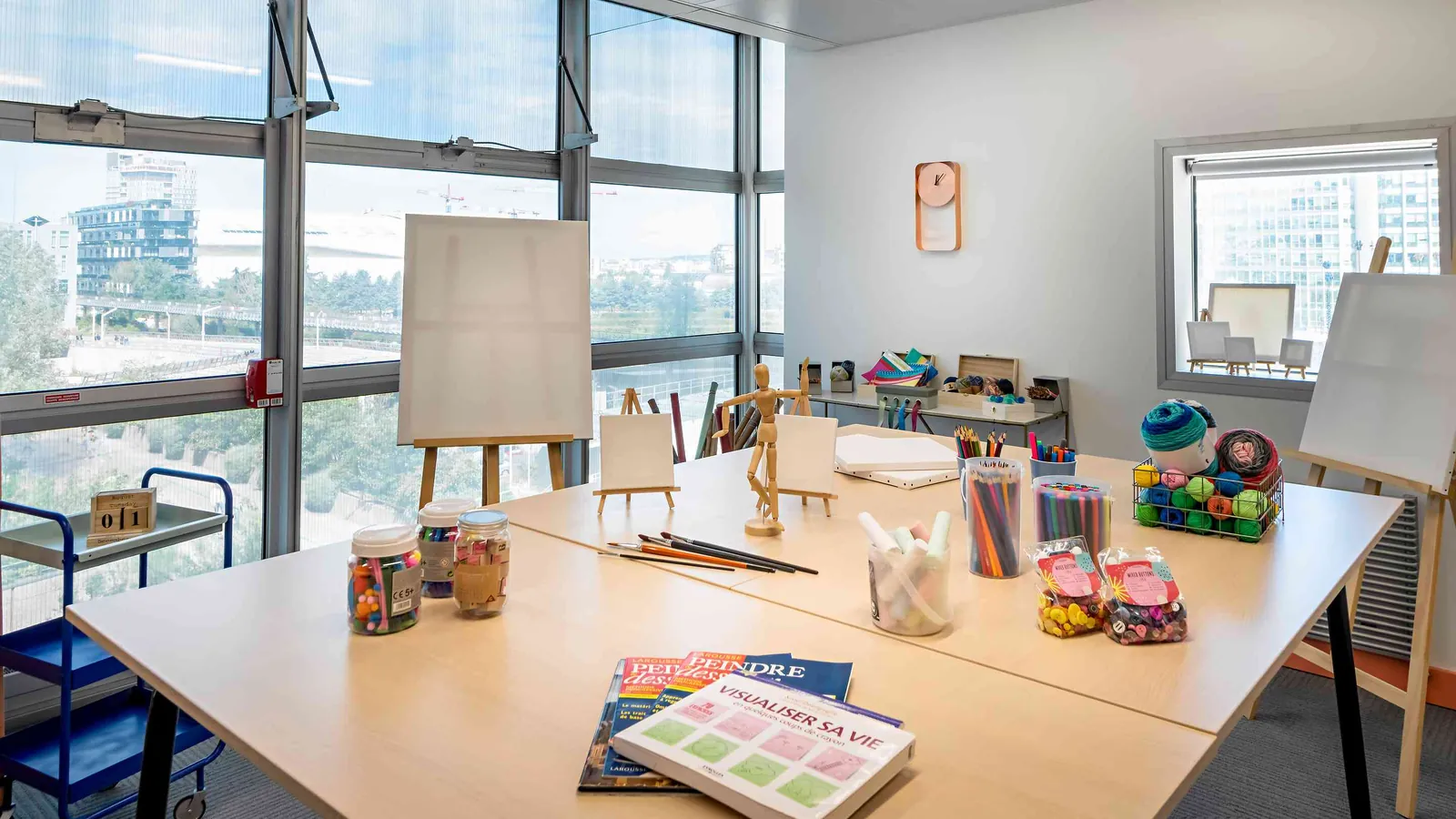 West Pavilion creative workshop table with easels, paints and daylight from large windows