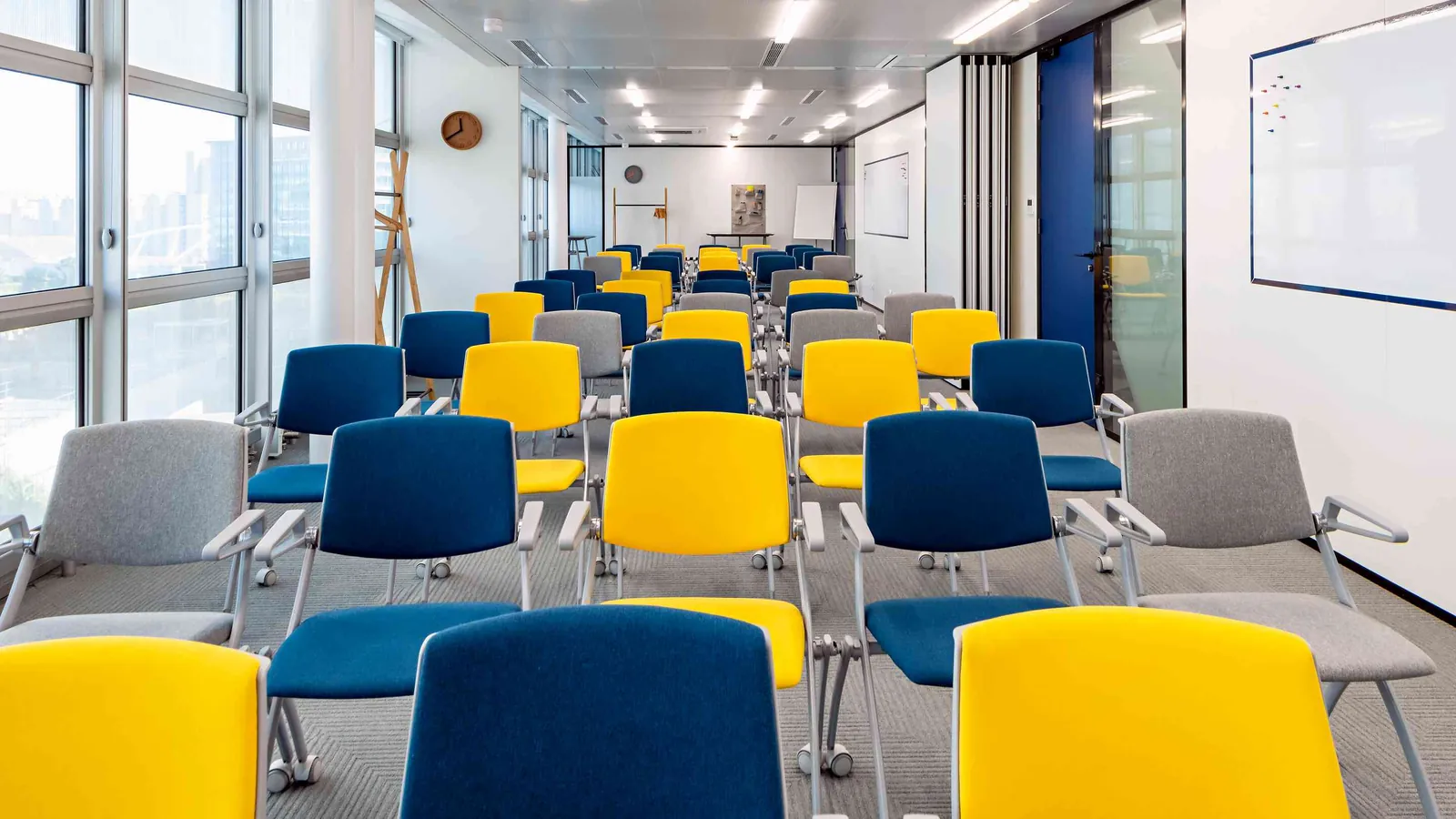 West Pavilion training room with blue and yellow chairs in rows beside large windows