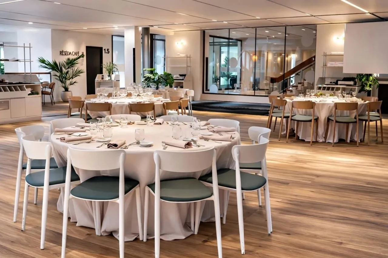 Round tables set for dinner with white linen and green chairs