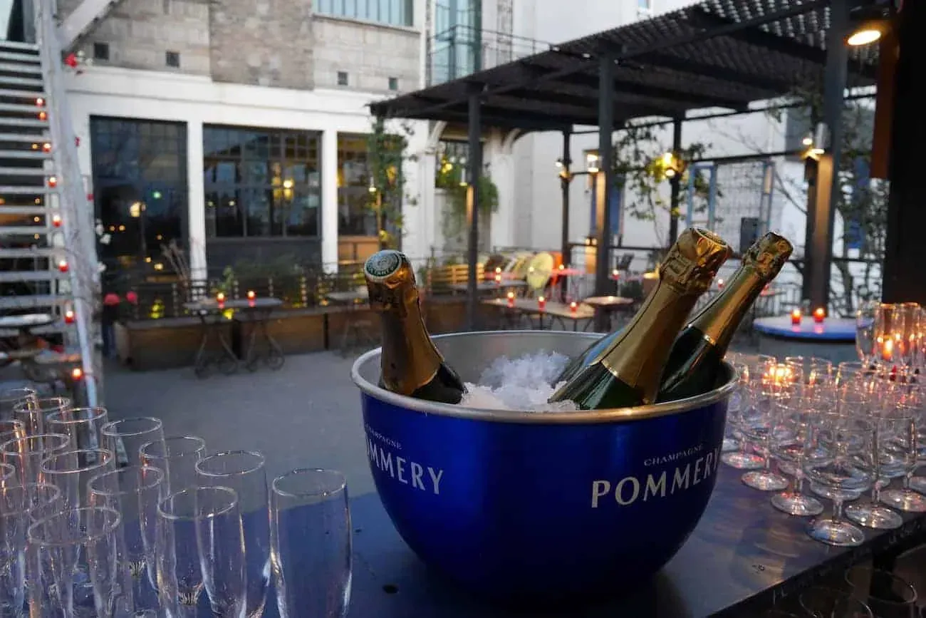 Champagne bucket and glasses set on a terrace under a pergola