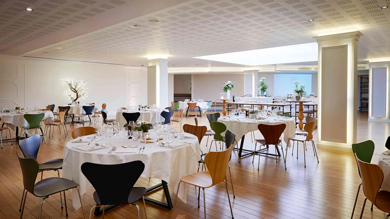 Moulding Salons banquet hall with round tables and white cloths set near the windows