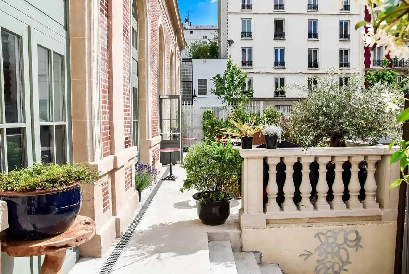 Terrace with a stone balustrade, planters and a brick building facade