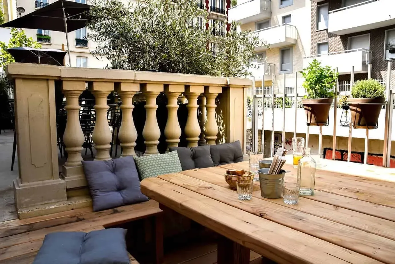 Terrace with stone balustrades, planters and a wooden table with cushioned benches