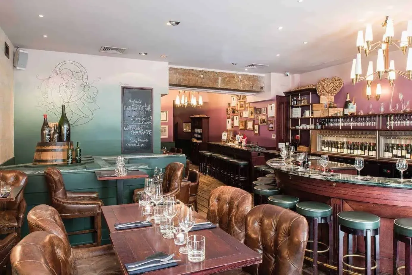 Vintage bar with a curved wooden counter, leather bar stools and a chandelier